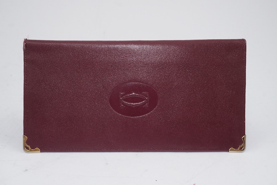 An assortment of Must de Cartier bordeaux leather accessories